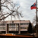 Budynek słowackiego parlamentu wśród jesiennych drzew, flaga na wietrze