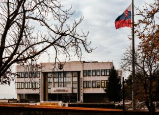 Słowacja po wyborach: co oznacza nowy rząd dla turystów Budynek słowackiego parlamentu wśród jesiennych drzew, flaga na wietrze