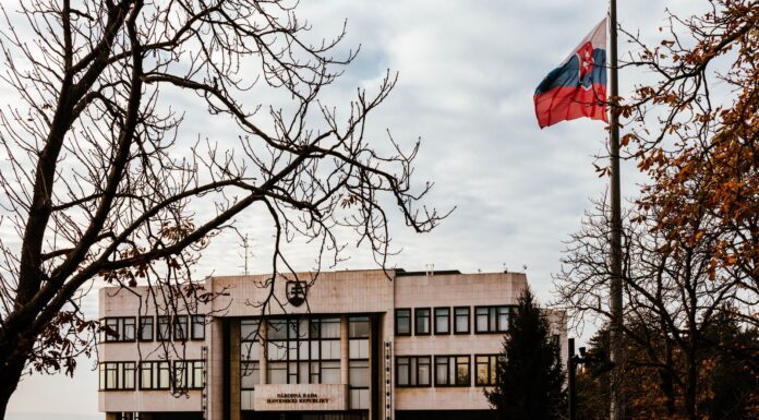 Słowacja po wyborach: co oznacza nowy rząd dla turystów Budynek słowackiego parlamentu wśród jesiennych drzew, flaga na wietrze