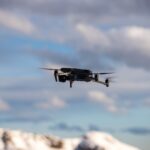 Dron lecący nad ośnieżonymi górami pod dramatycznym niebem