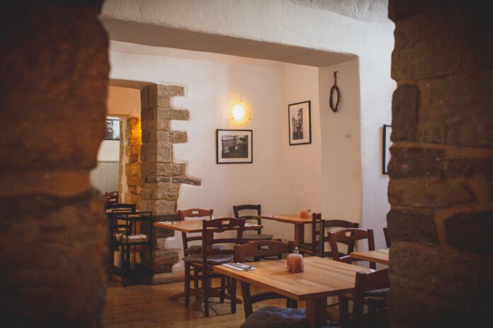 Przytulne wnętrze małej restauracji z drewnianymi stołami i rustykalnym wystroje Przytulne wnętrze małej restauracji z drewnianymi stołami i rustykalnym wystroje