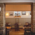Przytulne wnętrze restauracji z kamiennymi ścianami i drewnianymi stołami