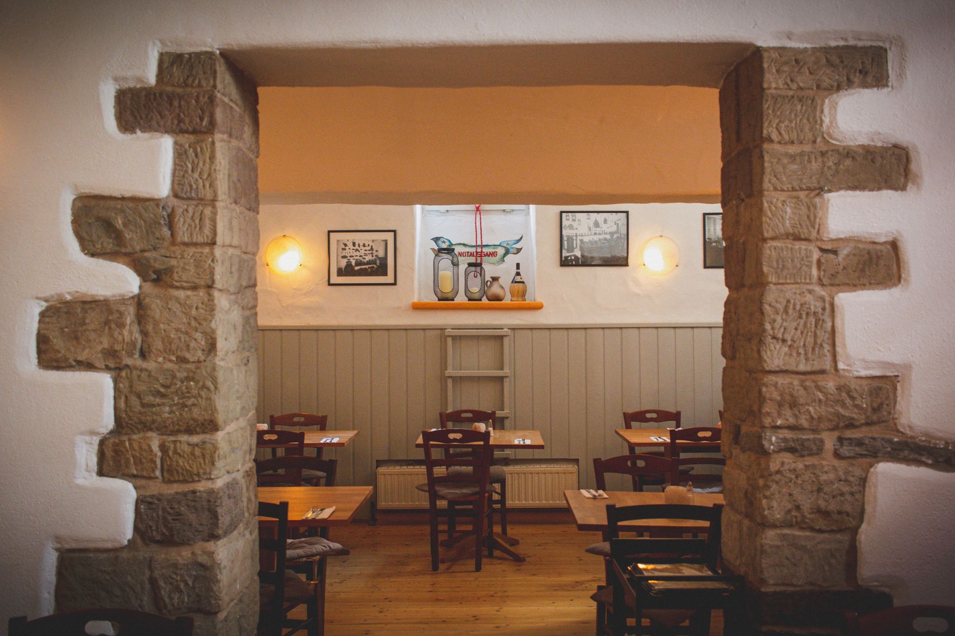 Przytulne wnętrze restauracji z kamiennymi ścianami i drewnianymi stołami