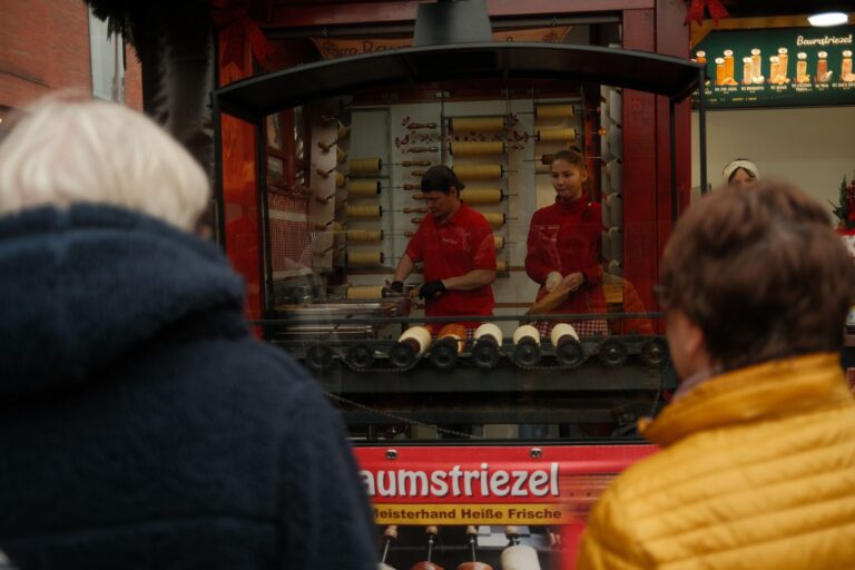 Sprzedawcy przygotowują kürtőskalács na świątecznym jarmarku